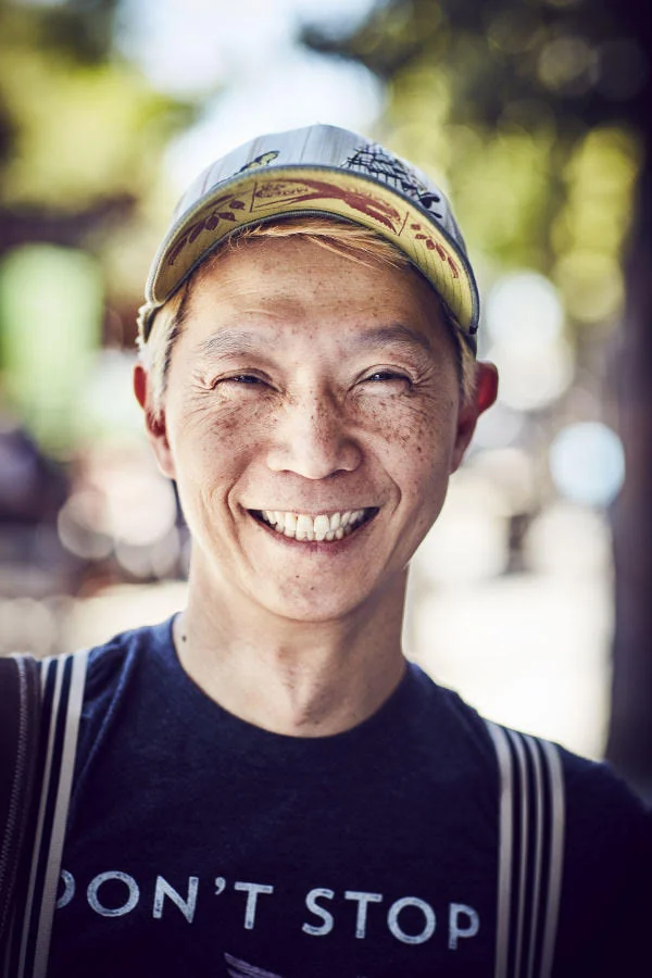 A man wearing a baseball cap poses in the street. In the Mission, San Francisco. Photography by portrait photographer Jon Enoch.