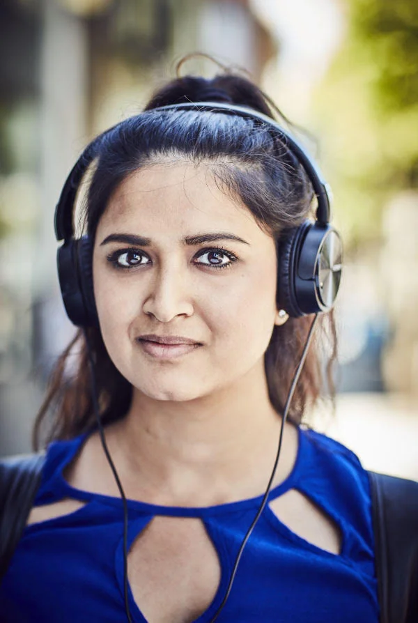 A women wearing over the ear headphones poses in the street. In the Mission, San Francisco. Photography by portrait photographer Jon Enoch.
