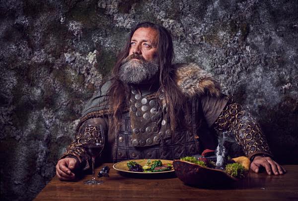 A man dressed in viking dress eats a meal. Photographer Jon Enoch