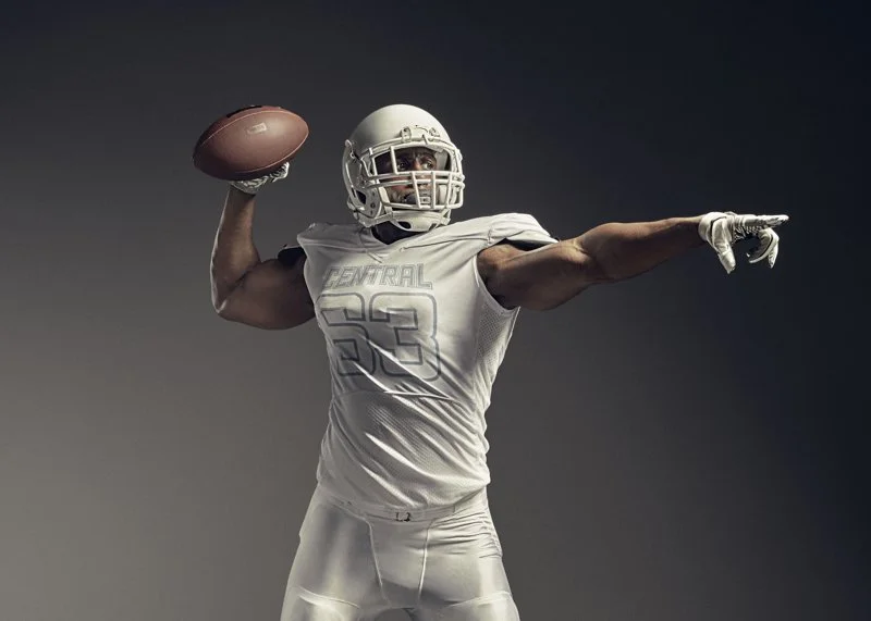 An American Football player throws the ball in the advertising studio shot by London based advertising, lifestyle and sports photographer Jon Enoch