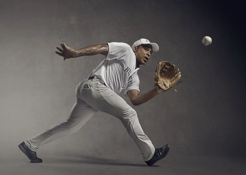 A baseball player runs to catch the ball, glove extended, in this dynamic sports shot by adverting photographer Jon Enoch