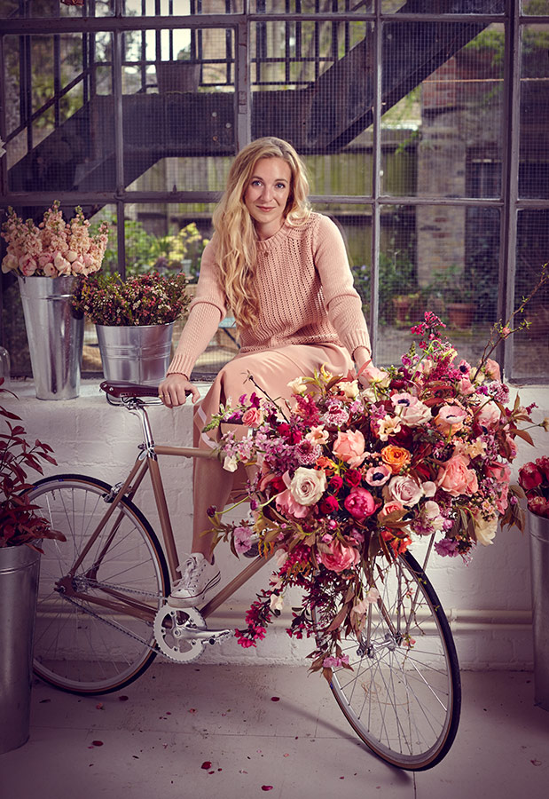 A women poses with flowers which she delivers to customers by bike in this image by lifestyle and portrait photographer Jon Enoch (Copy)