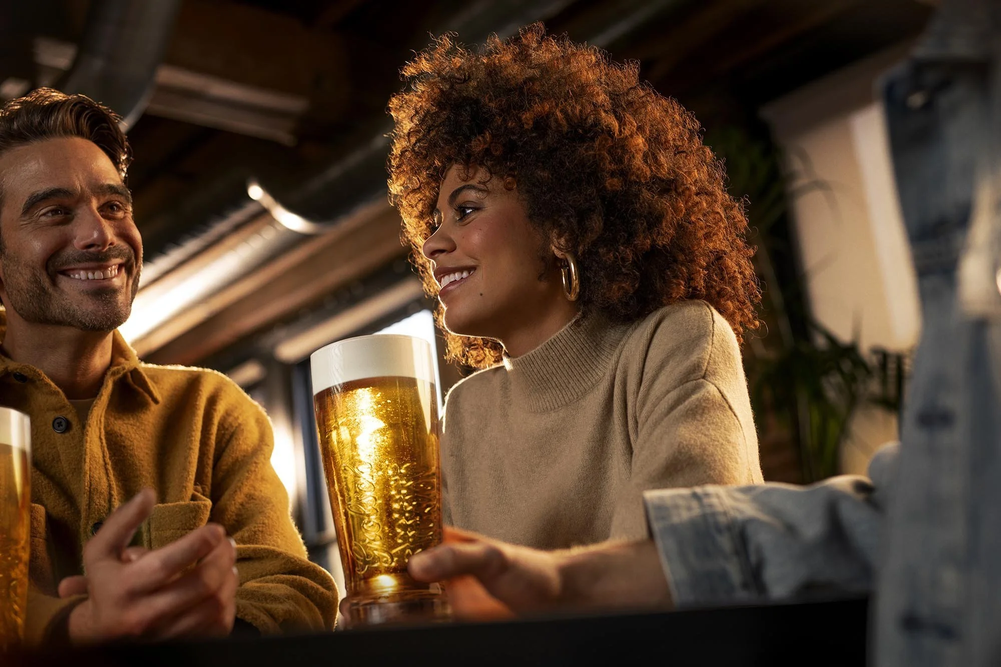 Friends chat around a table at a music venue and enjoy a beer in this lifestyle image by Jon Enoch