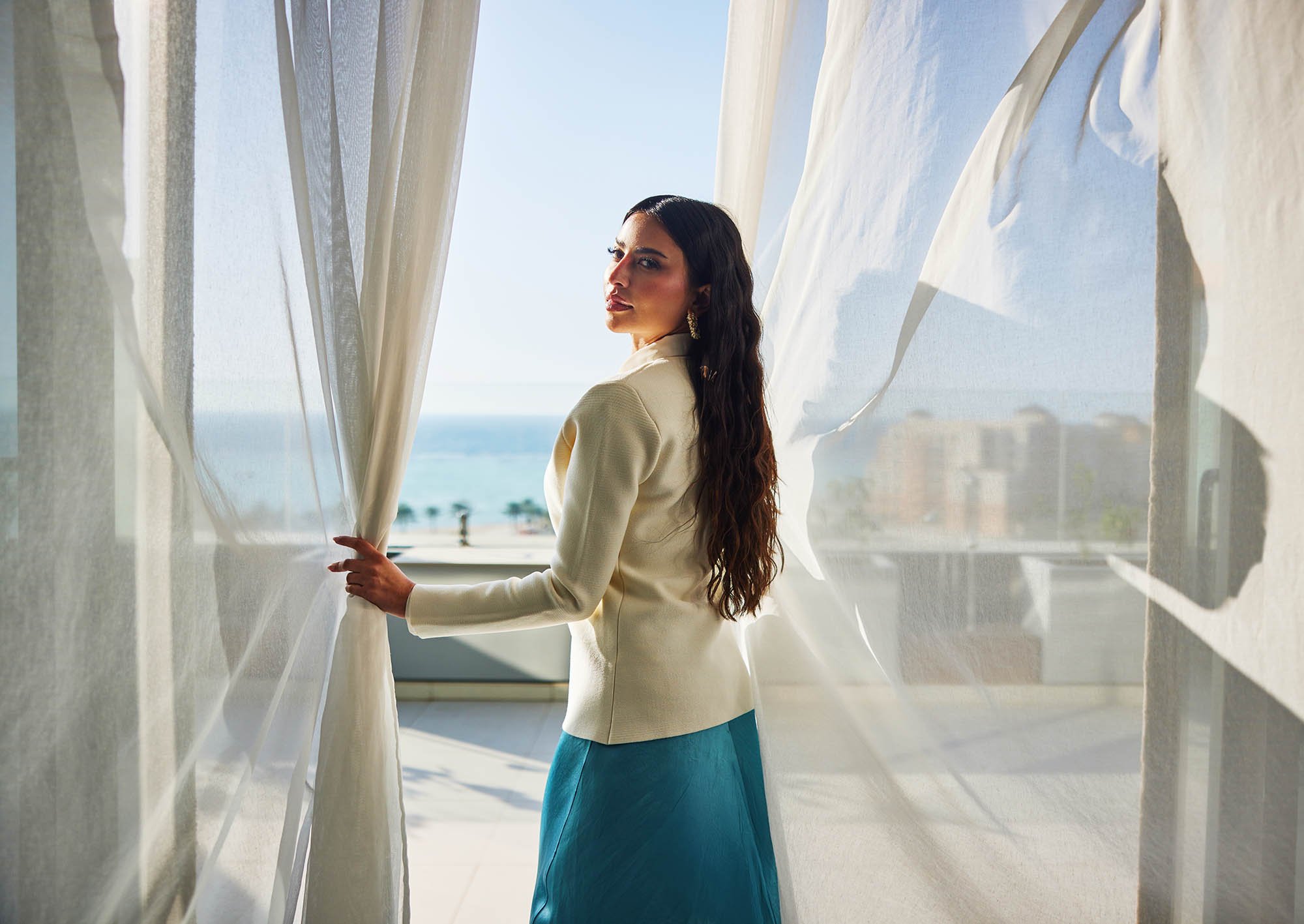 Lama Alakeel looks back over her shoulder as she walks out onto a balcony in this advertising image taken in Saudi Arabia for the NHC.