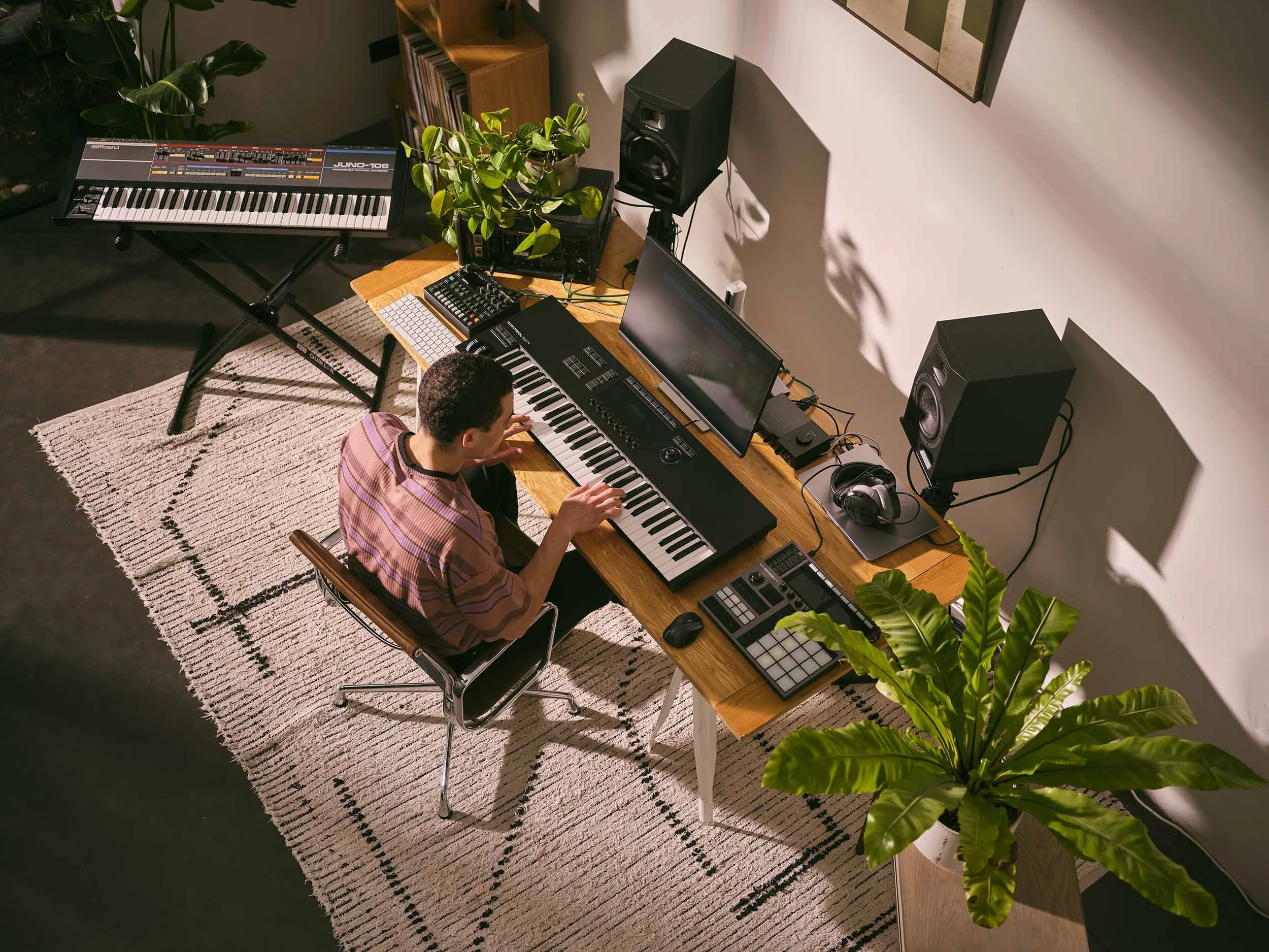 A man works away in him some recording studio this lifestyle image, he is pictured using and playing Native Instruments software and hardware which are used for music production, sound design, performance and DJing