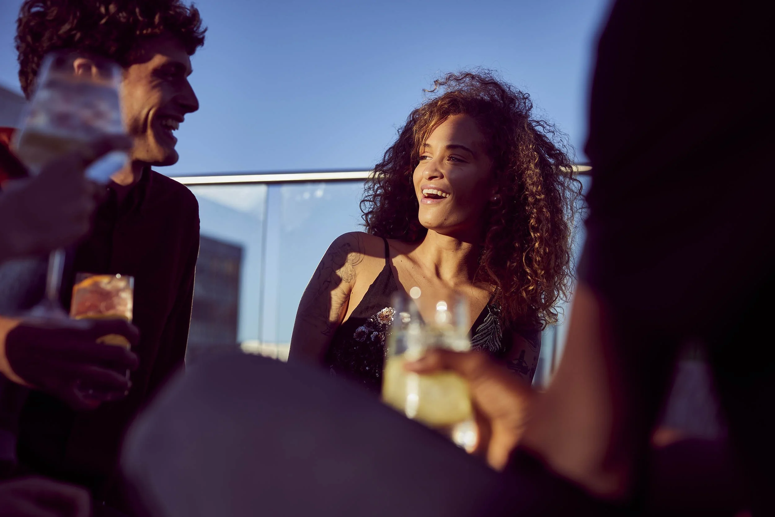 Friends chat and laugh as they enjoy summer drinks in this lifestyle image by Jon Enoch