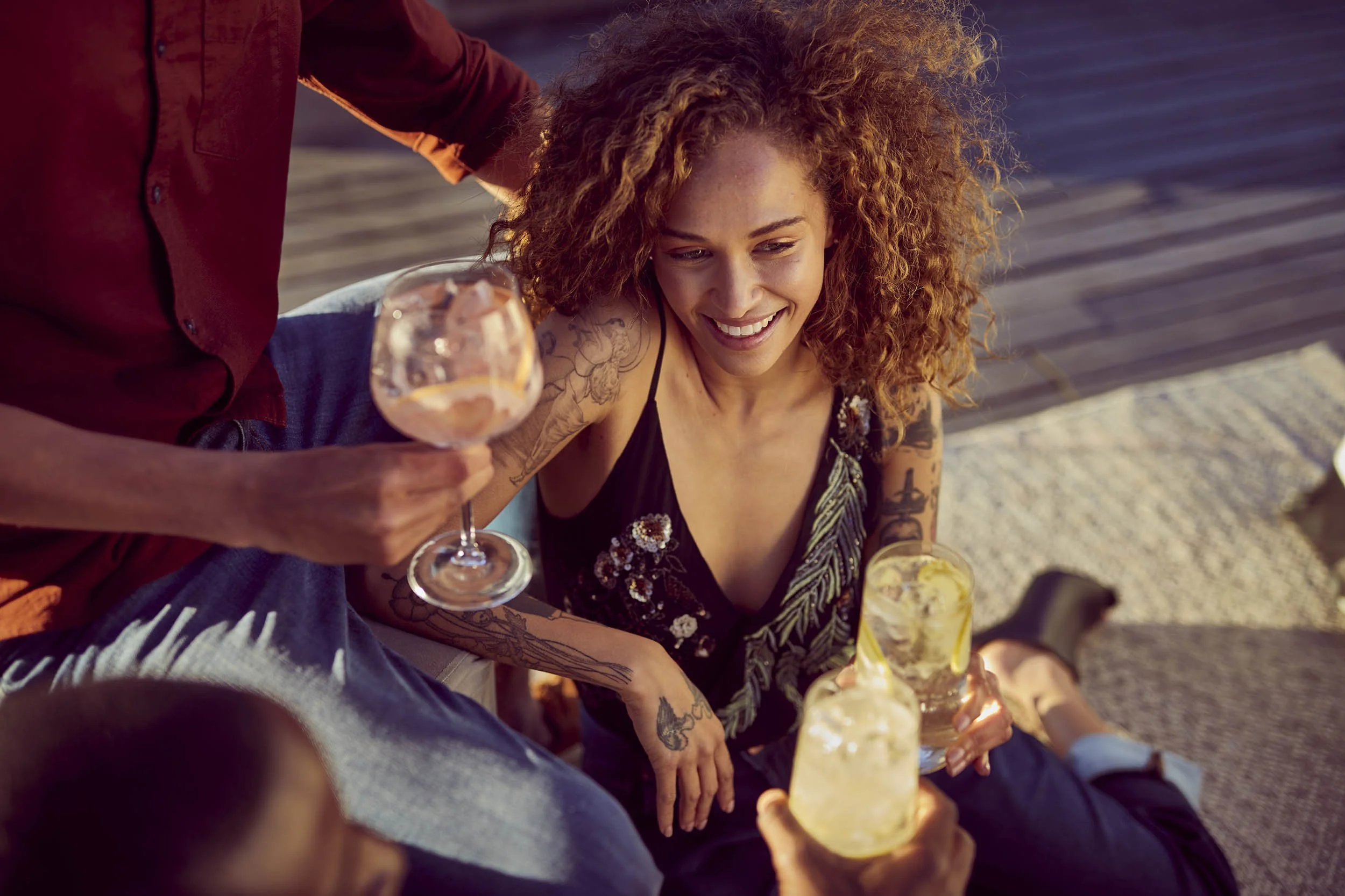 Refreshing summer drinks are enjoyed a group of friends on a rooftop in a late summertime - lifestyle image by Jon Enoch
