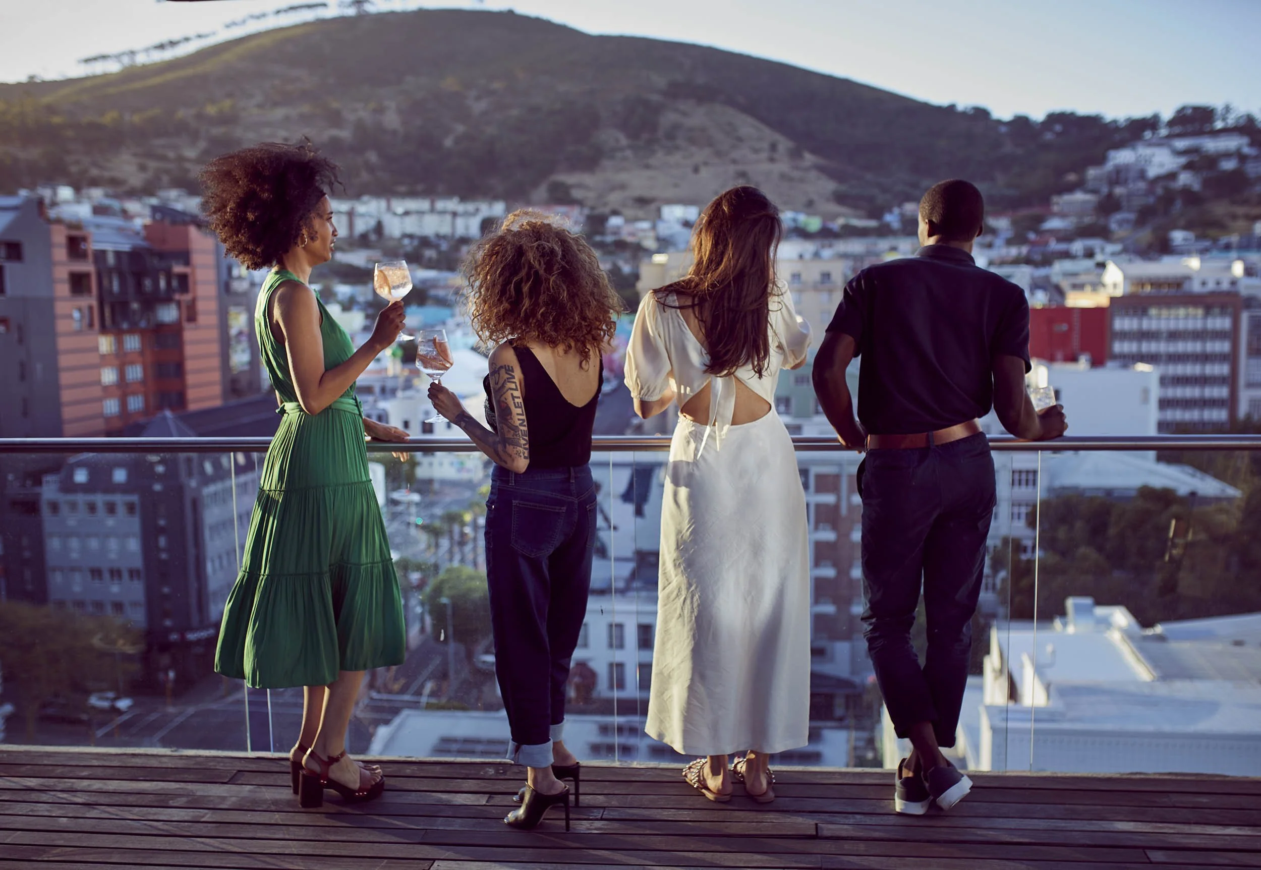 A group of friends watch the sun set over Cape Town as they enjoy some drinks - lifestyle photography by London based photographer Jon Enoch