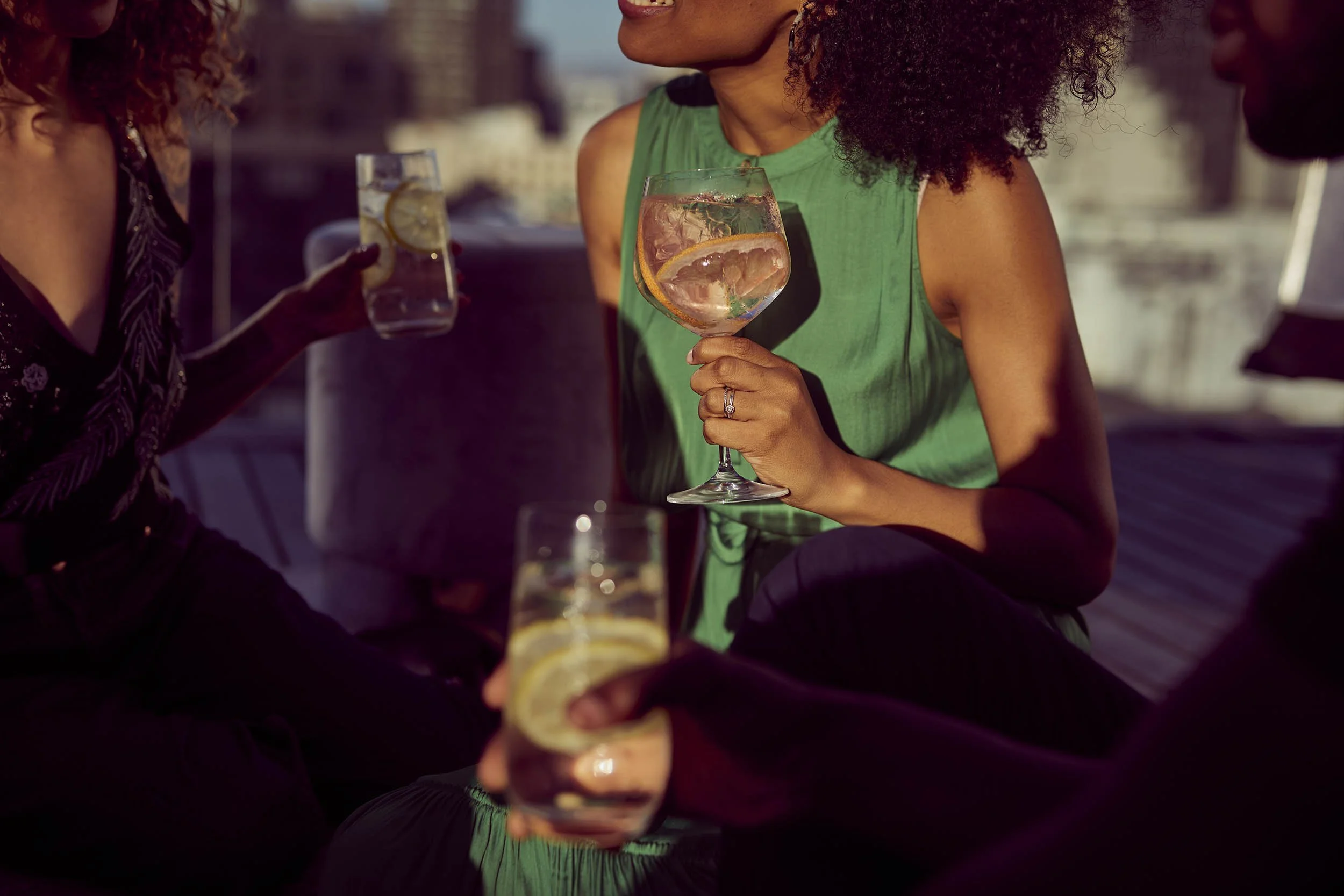 The warm summer sun hits a group of friends on rooftop in Cape Town as they enjoy summer spritz drinks - lifestyle drinks image by Jon Enoch