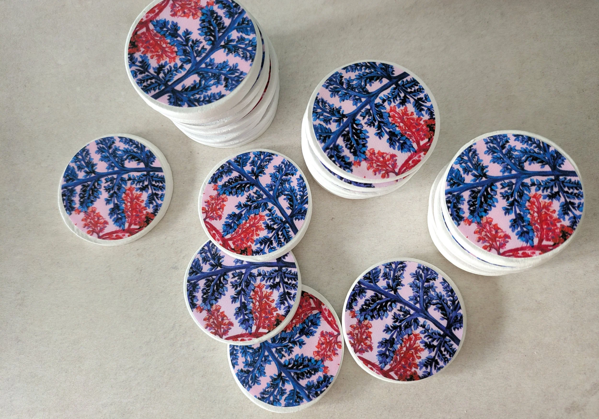 A stack of multiple handmade, round clay magnets. Each magnet features a unique botanical illustration, demonstrating the vibrant print and high-quality, small-batch craftsmanship from OH Arts.