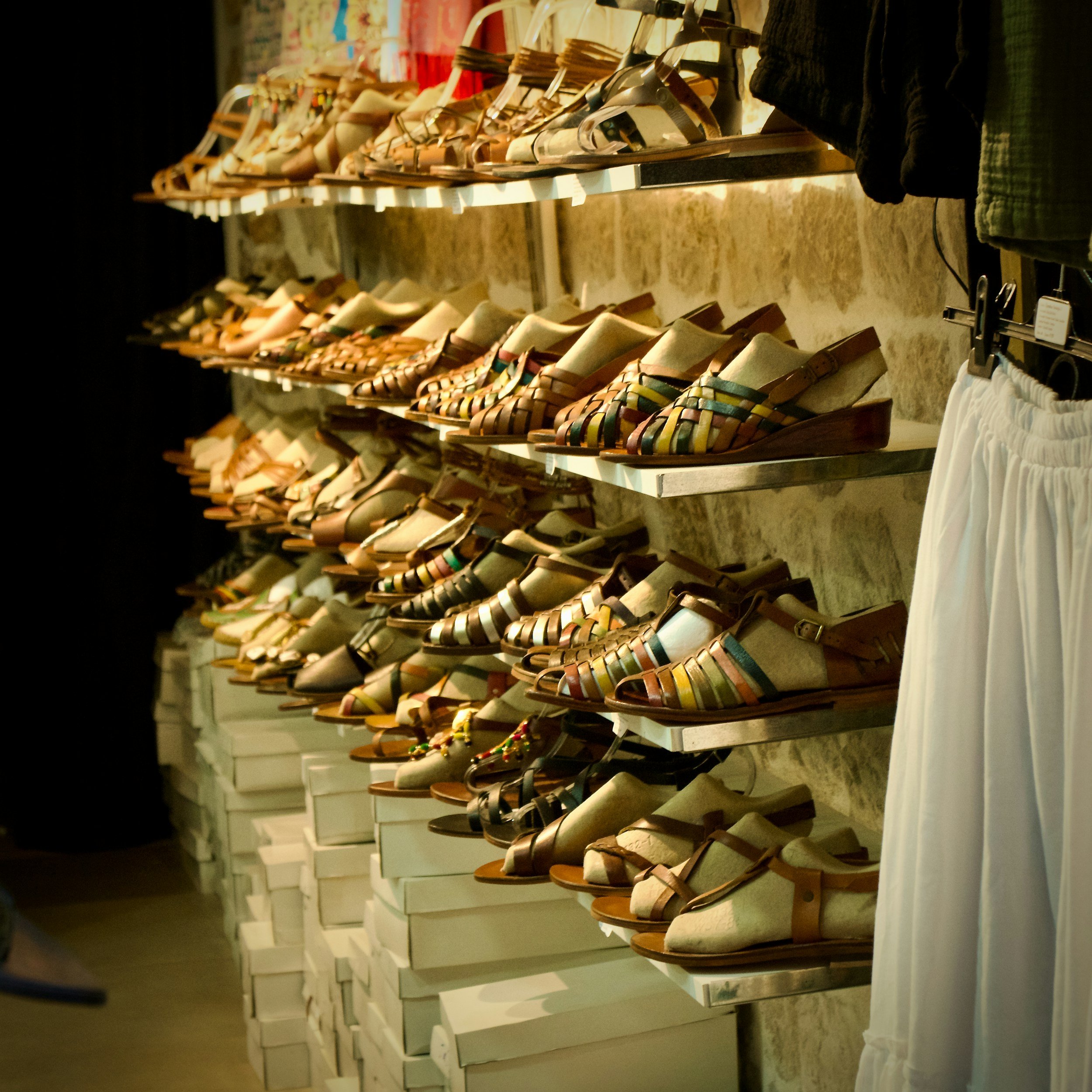A display of multiple pairs of sandals arranged on shelves in a shoe store.