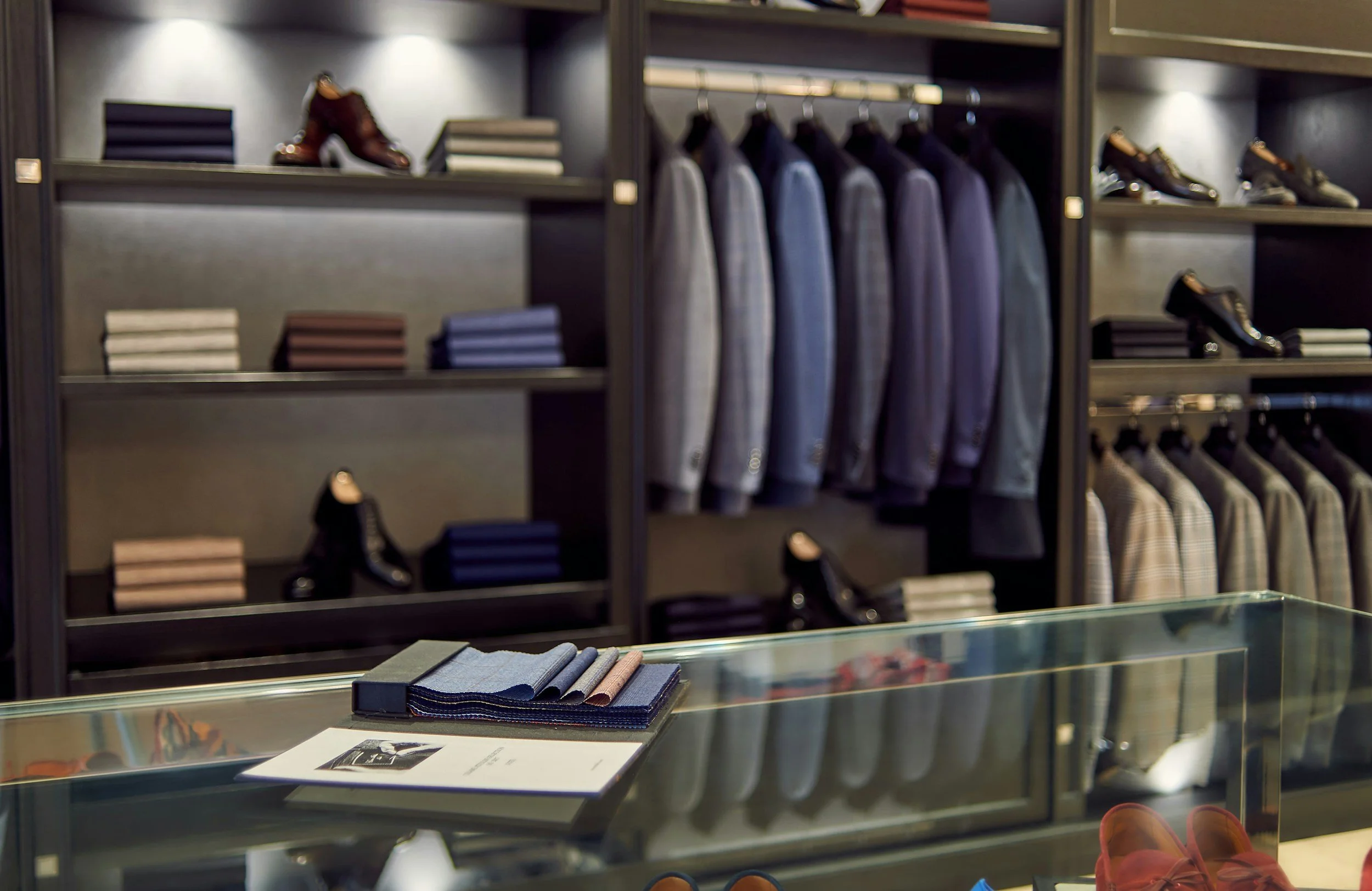 Clothing store display with suits, shoes, and ties on shelves.