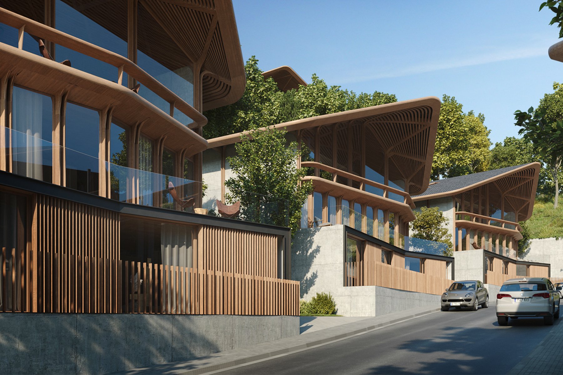 Conjunto de viviendas modernas de madera en una ladera con árboles verdes, coches en la calle y cielo despejado.