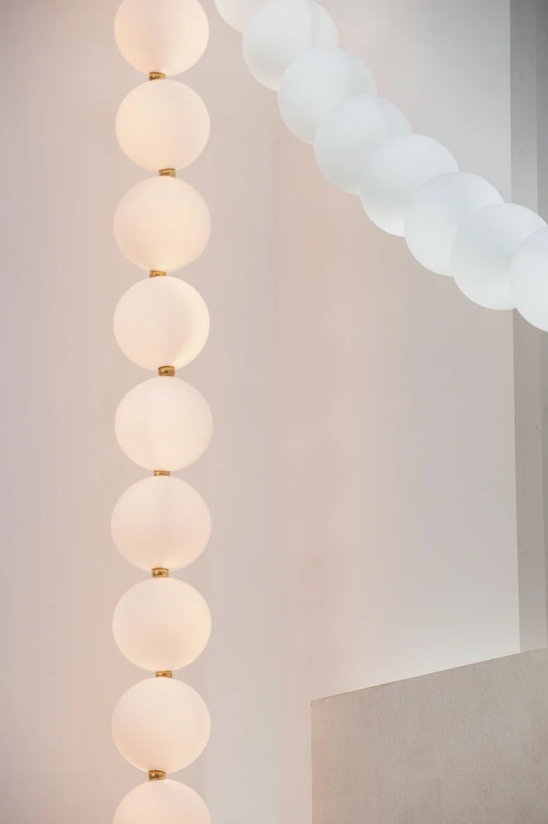 Chaînes de lampes rondes en forme de boules, éclairées et suspendues au plafond, couleur blanche, dans une pièce moderne.