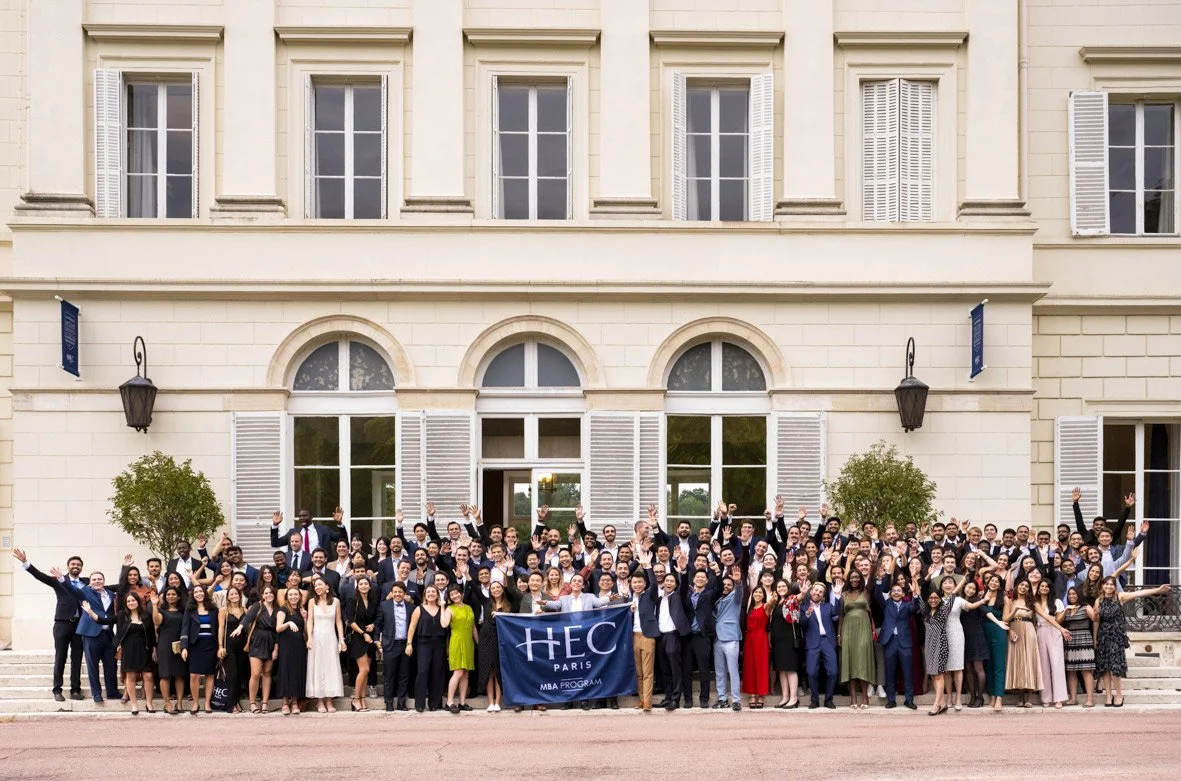groupe de diplômés posant pour une photo de classe devant un bâtiment historique