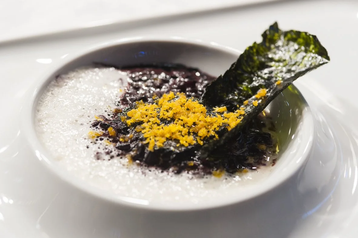 Soupe dans un bol blanc décorée de nori, de zeste de citron et de mousse blanche.
