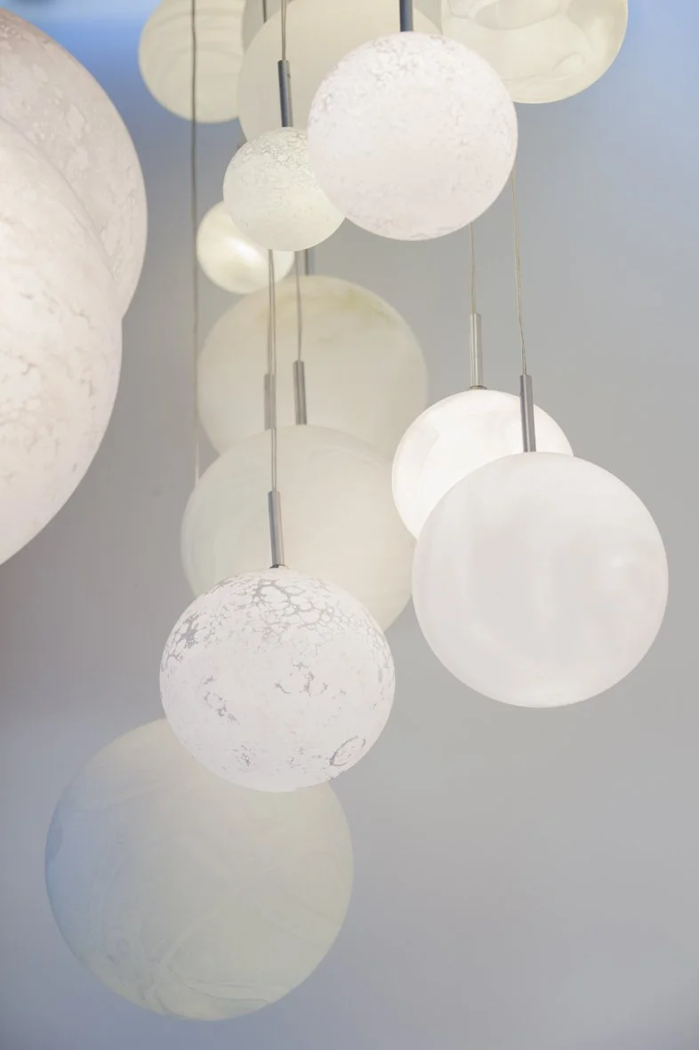 Lustre moderne avec plusieurs sphères en verre blanc suspendues.