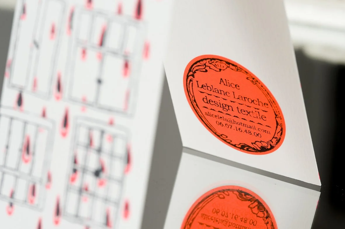 Carte de visite avec un cachet orange indiquant le nom Alice Leblanc Laroche, designer textile, avec une adresse email et un numéro de téléphone.