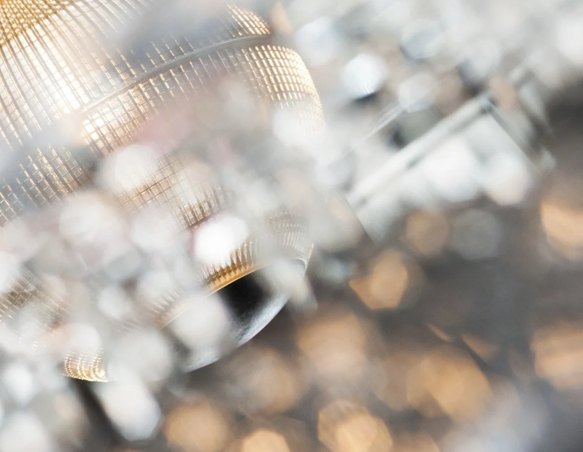 Gros plan d'une microphone à condensateur avec un filtre anti-pop, entourée de lumières floues.