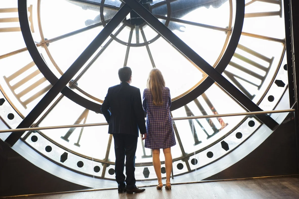 Un homme et une femme regardent une grande horloge dans un musée ou un bâtiment historique.
