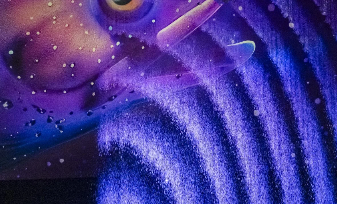 Un fond coloré avec des motifs de lumière violette, bleue et rose, ressemblant à des galaxies ou à des nuages cosmiques.