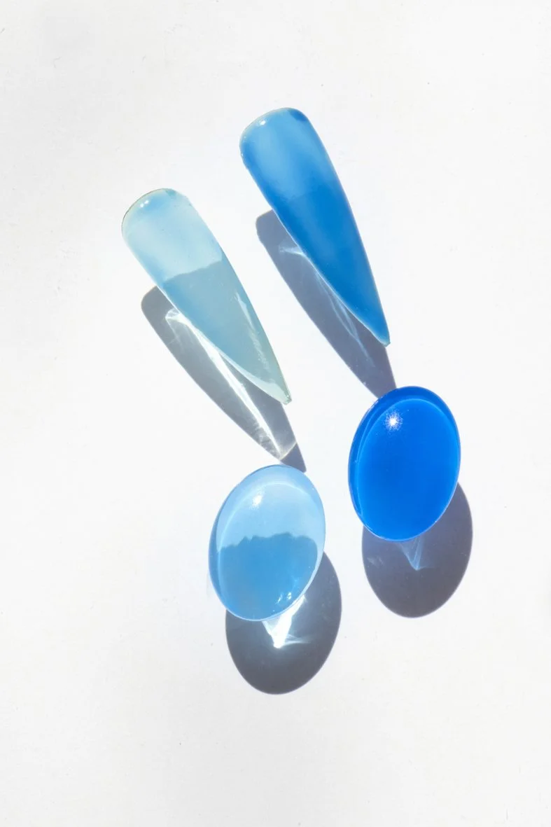 Deux verres de lunettes de soleil bleus translucides, avec des ombres portées sur un fond blanc