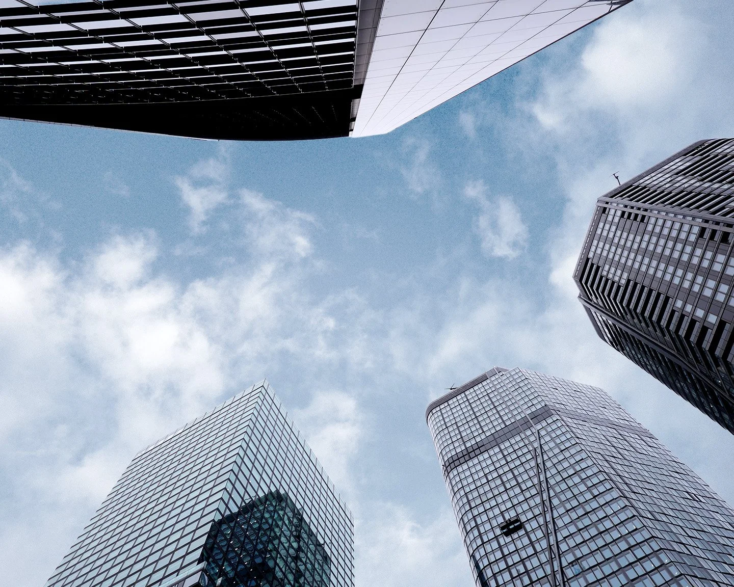 Blick nach oben auf moderne Wolkenkratzer mit Glasfassaden in einer Stadt, Himmel mit wenigen Wolken