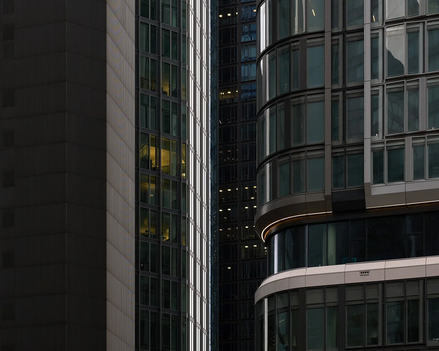 Nahaufnahme moderner Wolkenkratzer mit reflektierenden Glasfenstern und dunkler Fassade.