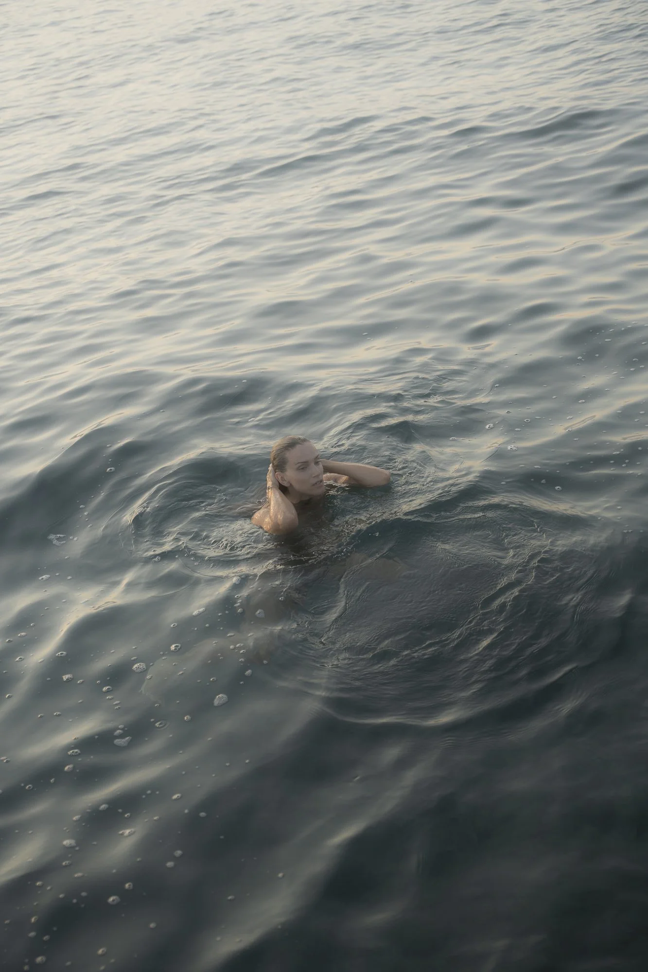 A woman swimming in a large body of water during the daytime.