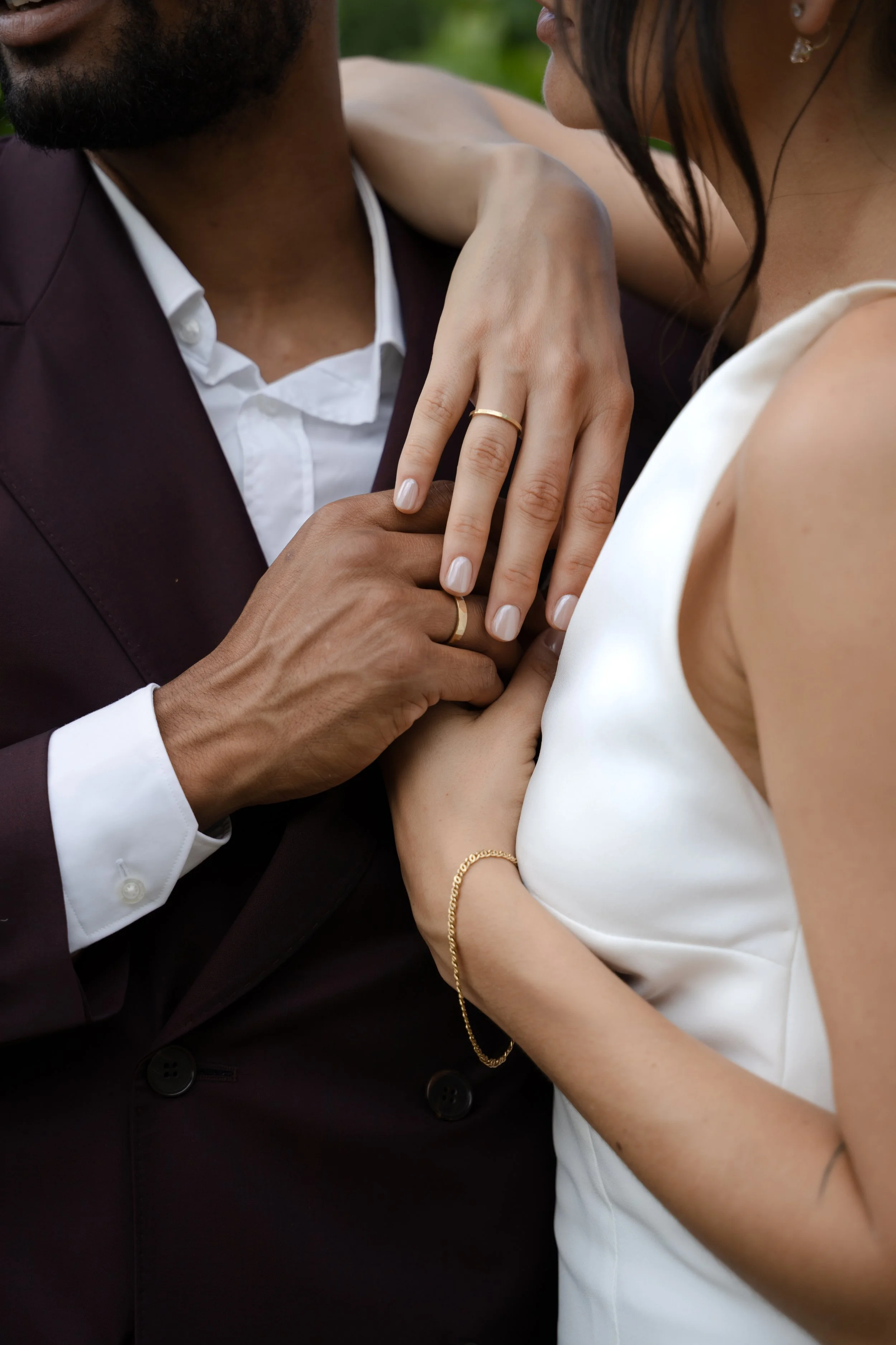 A couple sharing a moment of affection, with their hands and wedding rings prominently displayed.
