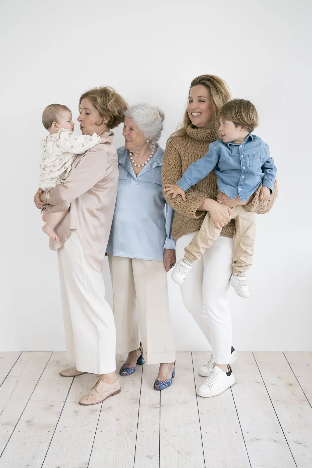 Multigenerational family of women and children smiling and interacting indoors against white background