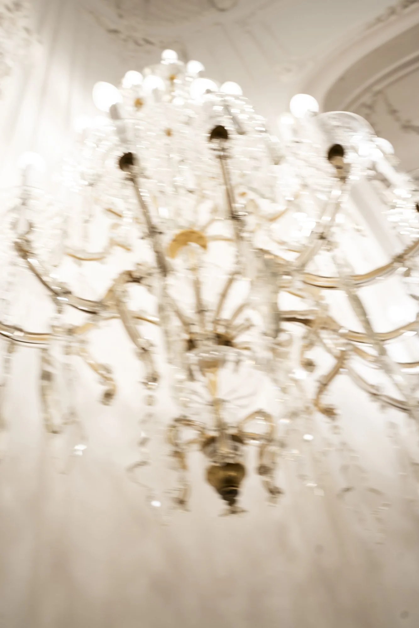 A grand crystal chandelier hanging from a ceiling with ornate decoration.