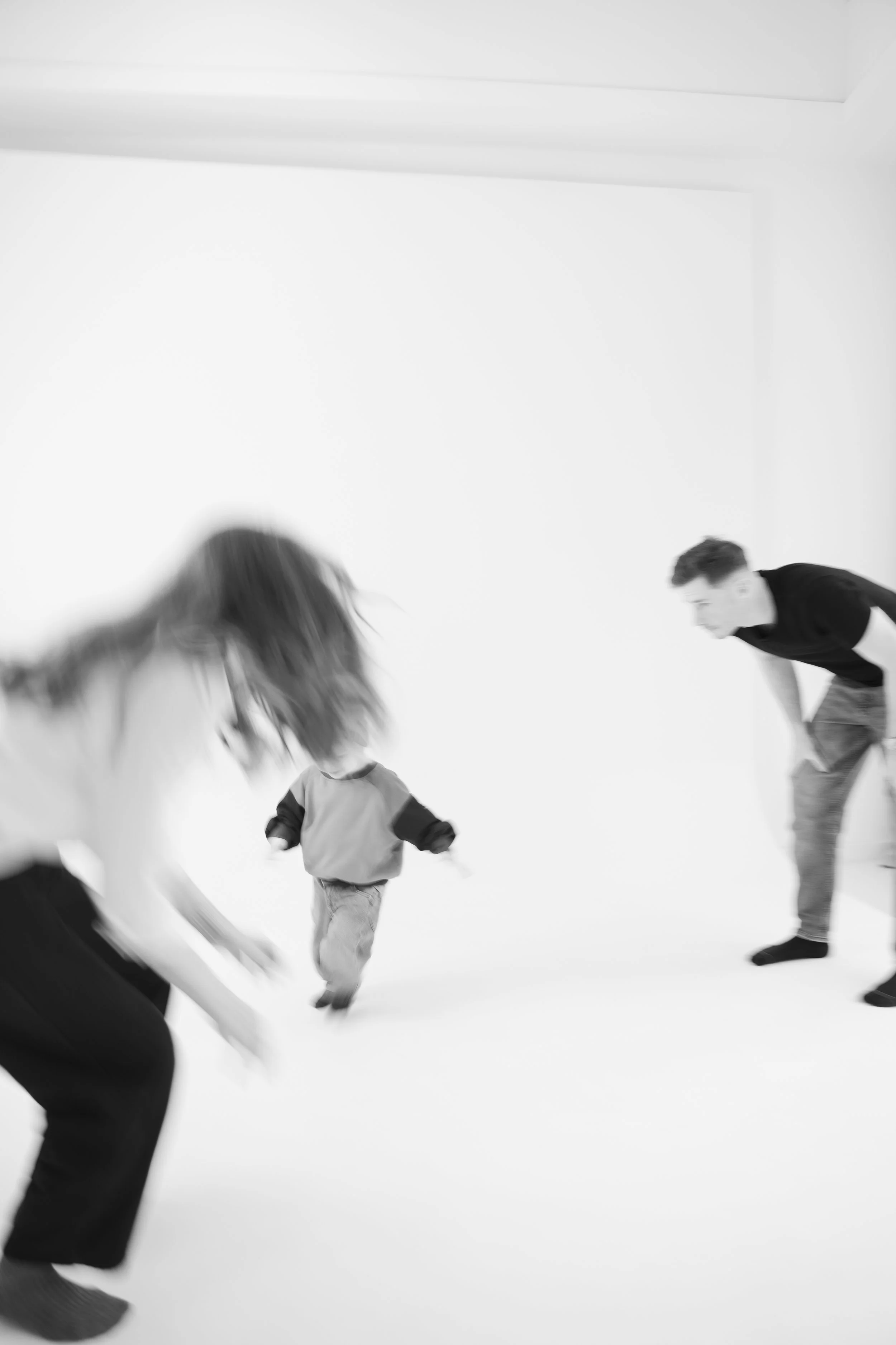 A black and white photo of three people in motion, on a white background, playing or dancing.