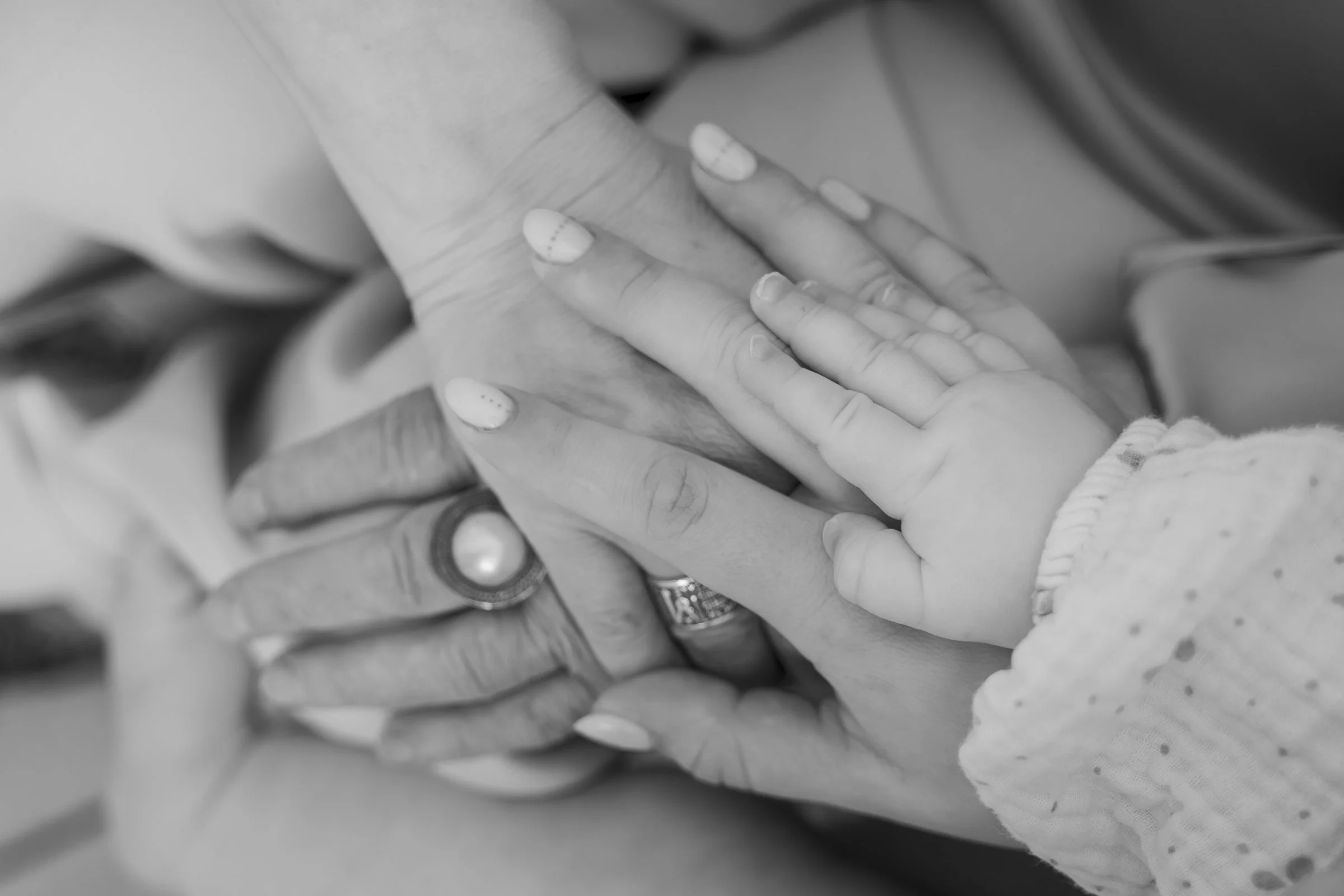 Multiple hands, including an adult's and child's, gently touching each other in a supportive gesture.