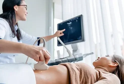 Sonographer performing an ultrasound on a pregnant woman in a medical clinic.