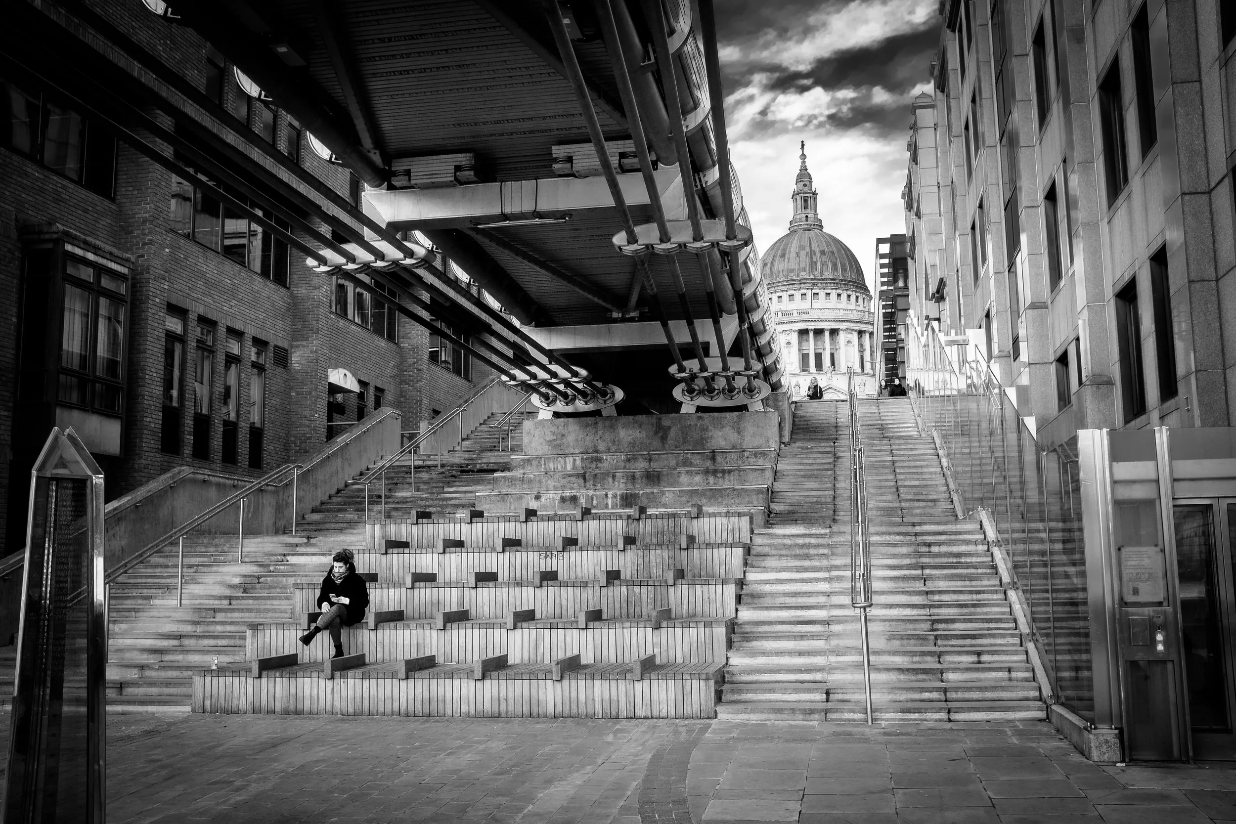 Relaxing on the steps under Millennium Bridge with St Paul's Cathedral in the background, London