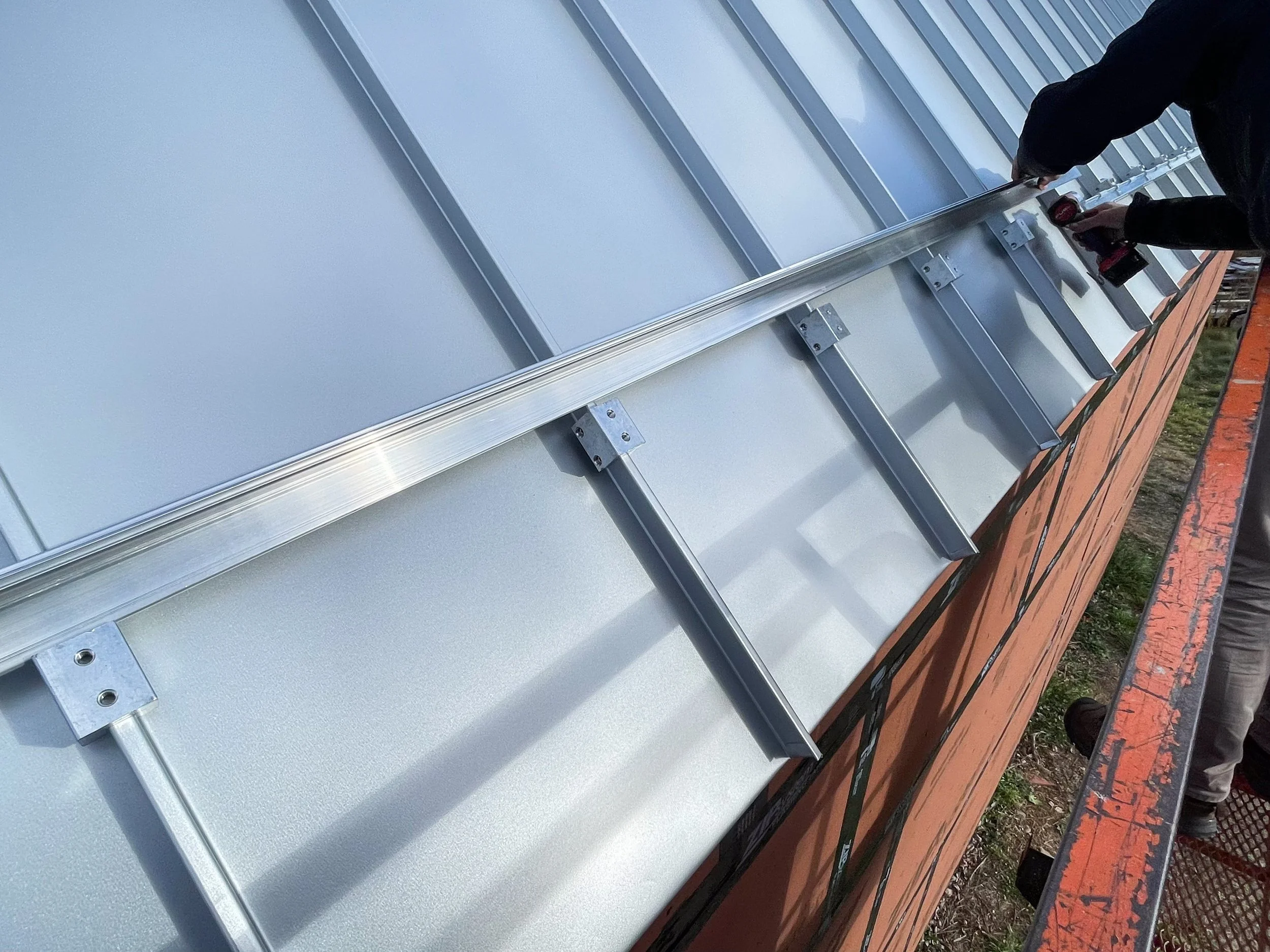 People installing or working on a solar panel on a rooftop with tools.