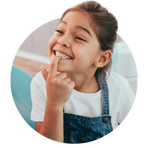 Smiling girl pointing at her teeth.