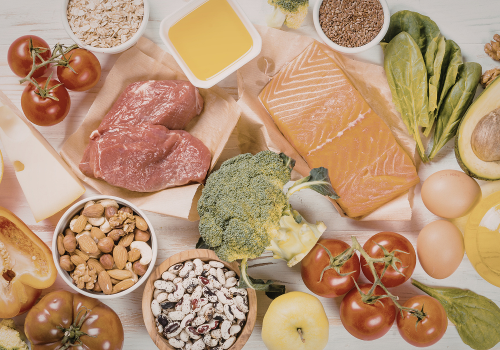 Nutrient-dense postpartum foods including bone broth, leafy greens, eggs, avocado, and salmon for new mother recovery