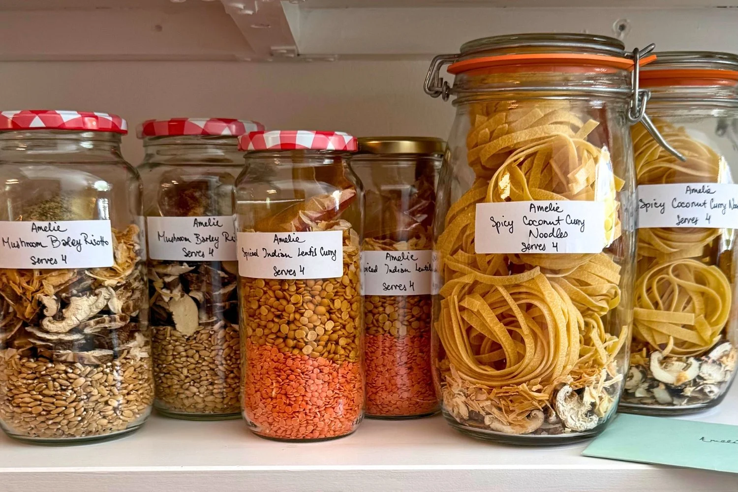 Shelf-stable postpartum pantry meals in glass jars: mushroom barley risotto, spiced Indian lentil curry and spicy coconut curry noodles