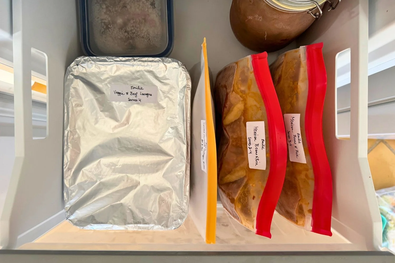 A week of postpartum meals fitting inside one standard home freezer drawer, stored upright to save space