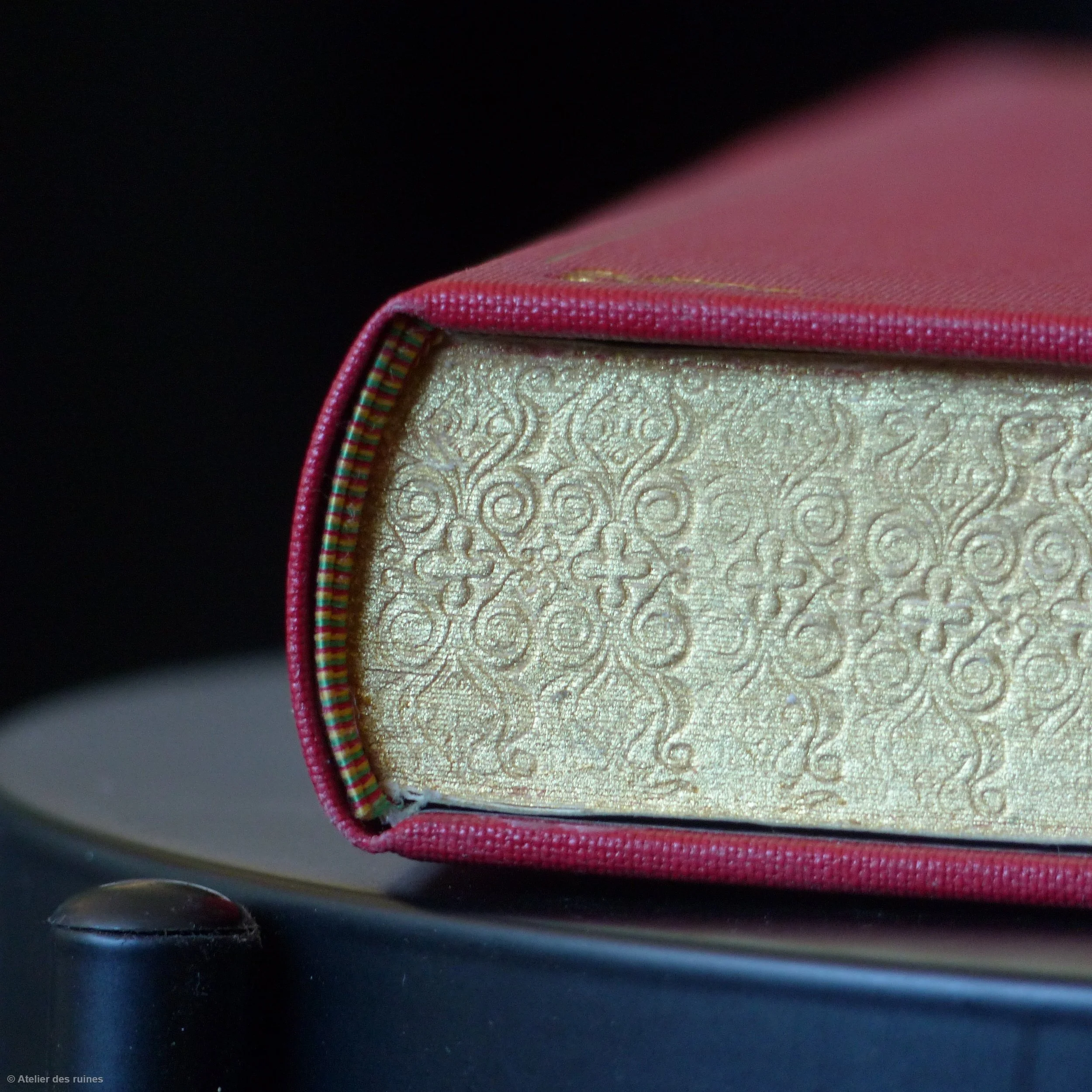 Une boîte de couture avec un tissu beige motif doré, entourée d'une bande de tissu rose à l'extérieur.