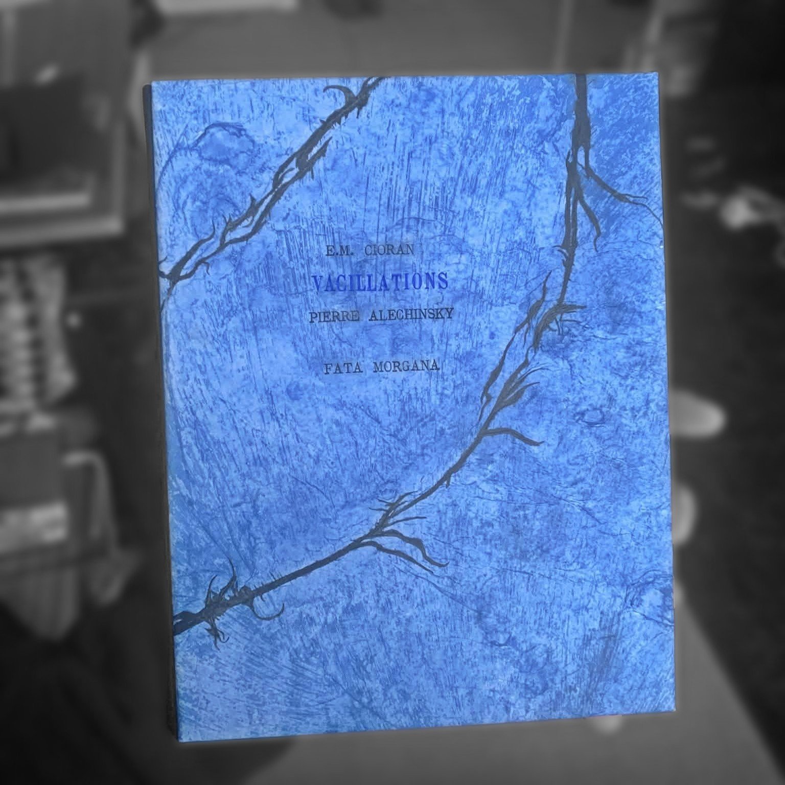 Livre bleu intitulé "Vacillations" avec des branches dessinées sur la couverture.