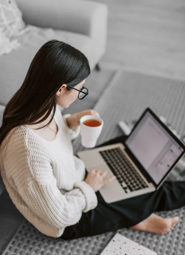 PLEB Group website migrations woman with a cup of coffee sitting with a laptop on her lap