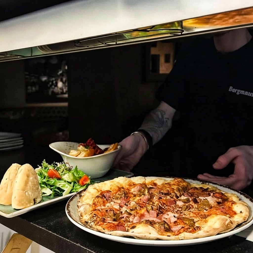 Bilde av en som serverer pizza og salat på Sand Bar og Restaurant