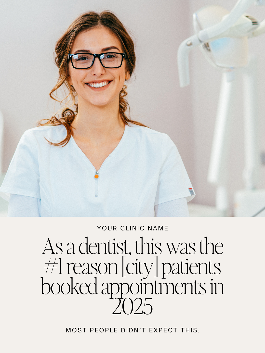 A smiling female dentist with glasses and curly hair, wearing a white dental coat, sitting in a dental clinic with dental equipment visible in the background.