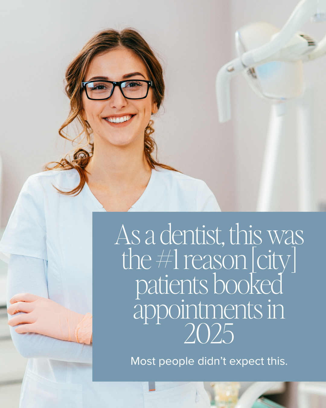 A smiling female dentist wearing glasses and dental scrubs standing in a dental clinic with dental equipment visible in the background.