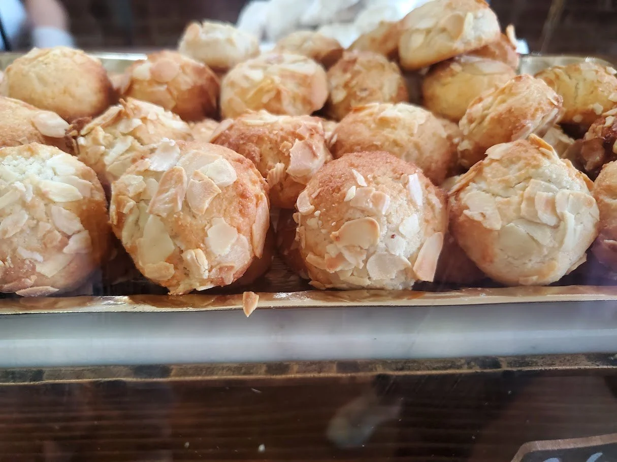 A tray of round almond pastry balls with sliced almond toppings.