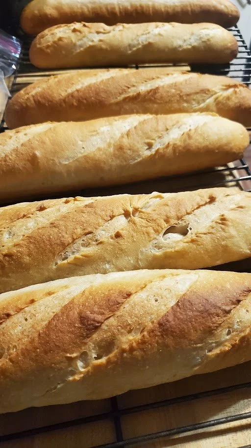 Six freshly baked baguettes cooling on a wire rack.