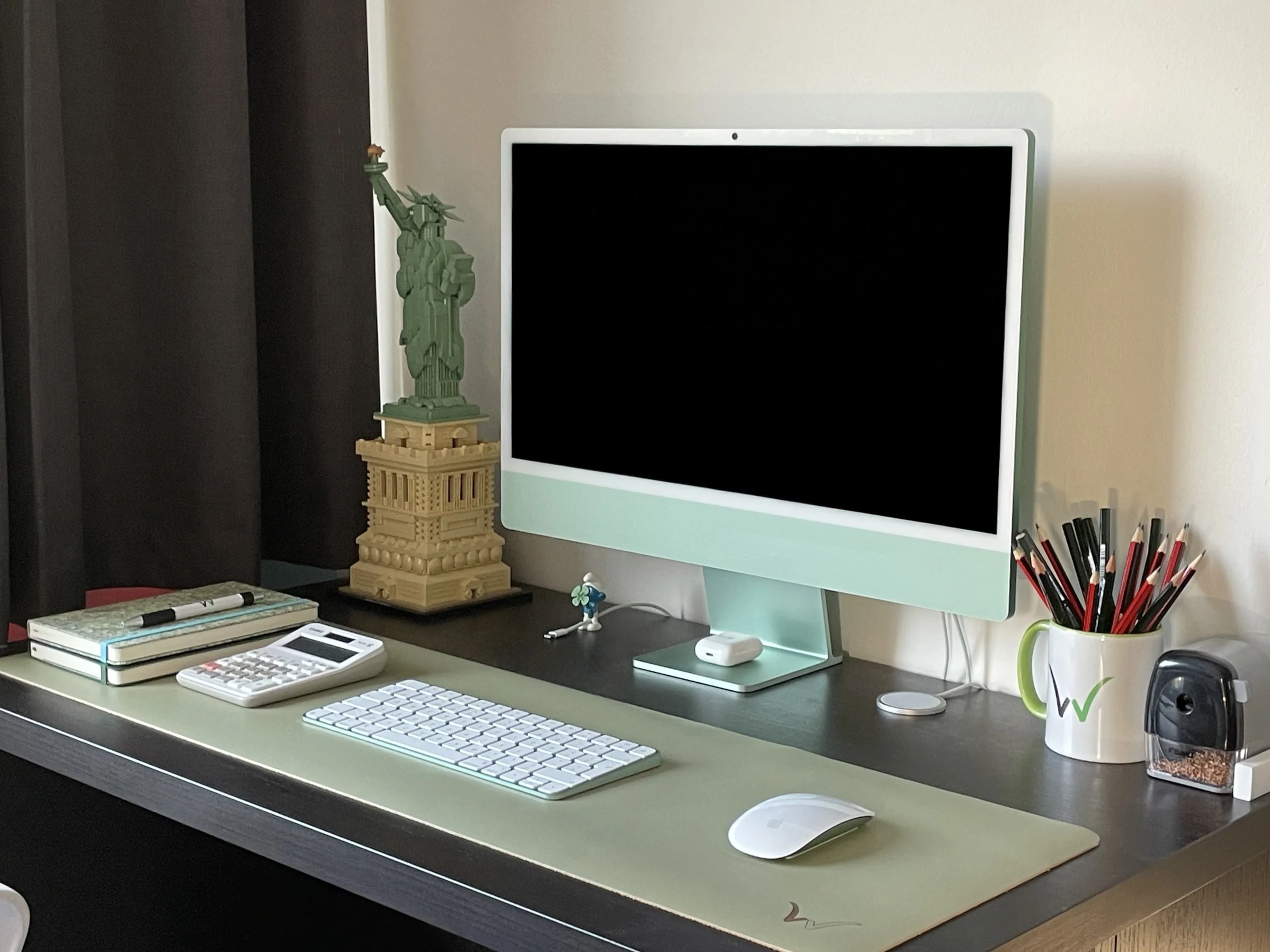 A desk with computer, calculator and note books.